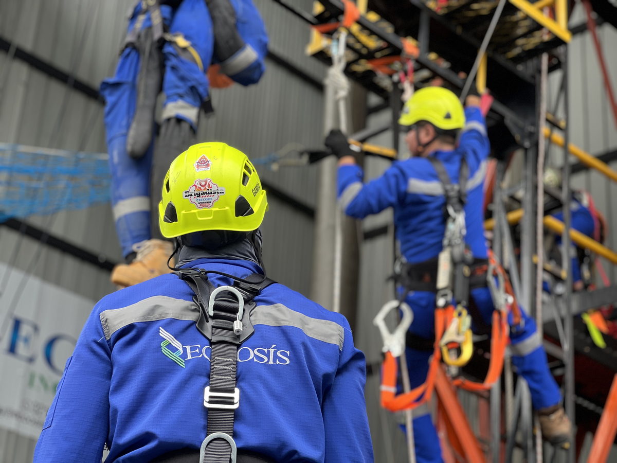 Dos participantes con arnés completo y casco durante una maniobra en la estructura de entrenamiento en alturas.