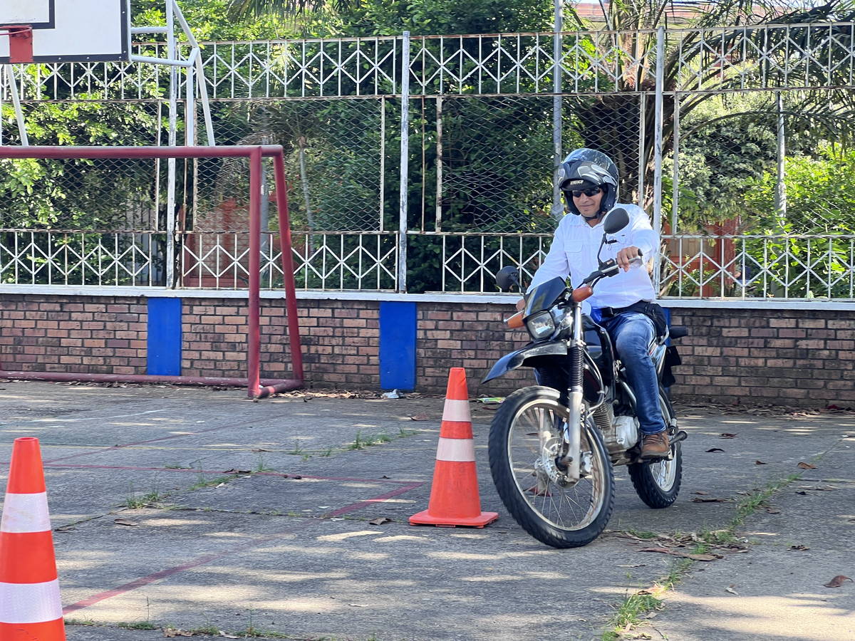 Motociclista con casco recorriendo un circuito de conos durante una práctica de habilidades de conducción.